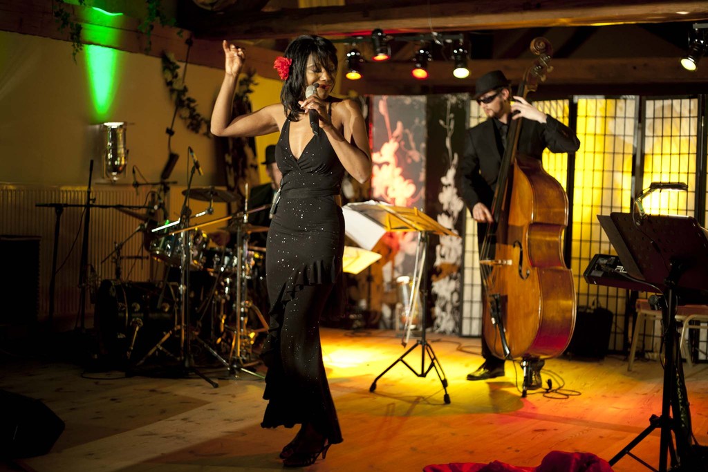 Heiße Rythmen auf der Bühne. Lola und ihre Band, eingehüllt in Bühnenlicht und bombastischen Sound. Bobby Blue erzählt dabei von Lolas Geschichte, die sich in Chicago und am Ort des Auftritts abspielt.